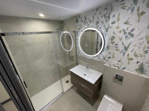 y baño con ducha, lavabo y espejo. en Apartamentos Aljama en Burgos
