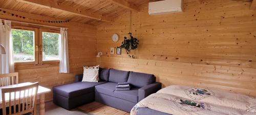 una sala de estar con un sofá azul en una cabaña de madera en Agnes Bed and Breakfast, en Bække