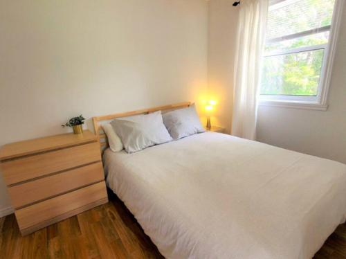 Un dormitorio con una gran cama blanca y una ventana en Les Refuges des Monts en Saint-Tite-des-Caps