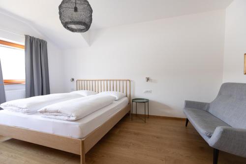 - une chambre blanche avec un lit et un canapé dans l'établissement Schöne Wohnung am Stadtrand von Meran Valentinhof, à Merano