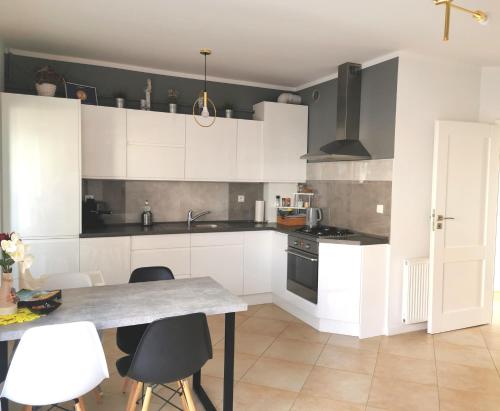 a kitchen with white cabinets and a table with chairs at Apartamenty Wybrzeże Laguna II in Ustronie Morskie