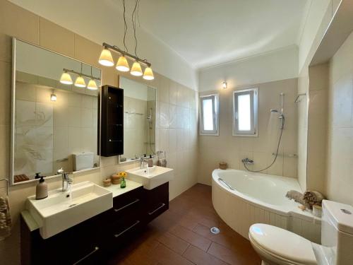ein Badezimmer mit zwei Waschbecken, einer Badewanne und einem großen Spiegel in der Unterkunft Apollon Paian , Luxury Nature Relax in Lefkada Town