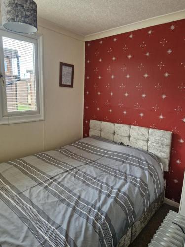 a bedroom with a bed with a red wall with stars at Beautiful 2-Bed Chalet in Mablethorpe in Mablethorpe