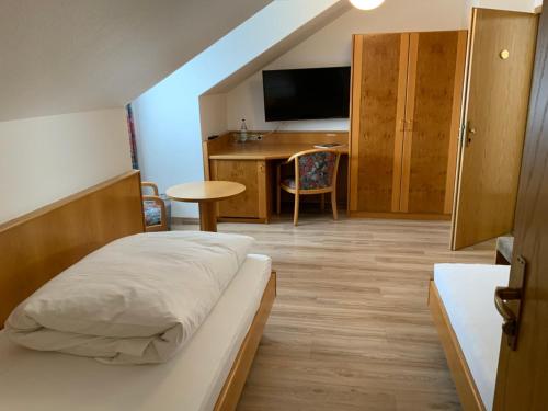 a bedroom with a bed and a desk with a television at Gasthaus Sonne in Hohenstadt