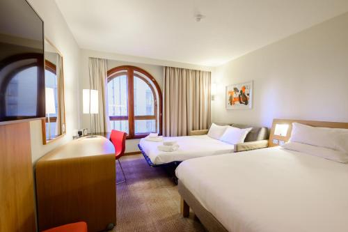 a hotel room with two beds and a sink at Novotel Birmingham Centre in Birmingham