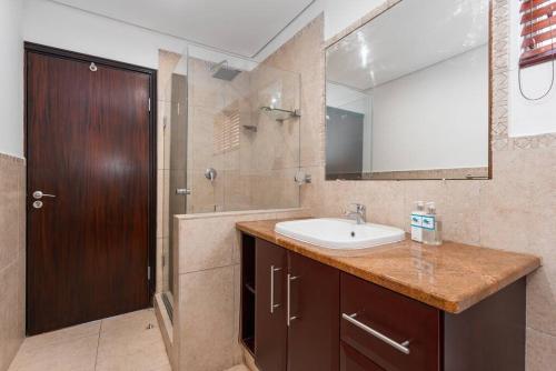 La salle de bains est pourvue d'un lavabo et d'une douche avec un miroir. dans l'établissement G1Bermuda-Oasis on Willard Beach, à Ballito
