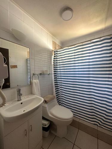 a white bathroom with a toilet and a sink at Cabañas Florencia La Serena in La Serena