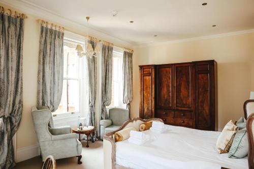 a bedroom with a bed and two chairs and a window at Mount Ephraim B&B in Hernhill