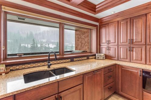 een keuken met houten kasten, een wastafel en een raam bij Exclusive 4 Bedroom Ski In, Ski Out Vacation Rental With Hot Tubs And Heated Outdoor Pool In Lionshead Village in Vail