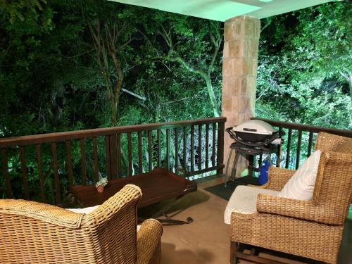 eine Terrasse mit 2 Stühlen und einem Grill auf einer Terrasse in der Unterkunft Tranquil Garden Nest in Nelspruit