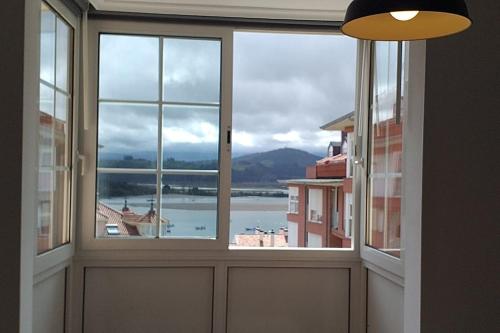 a room with three windows with a view of the water at Dúplex Saja in San Vicente de la Barquera