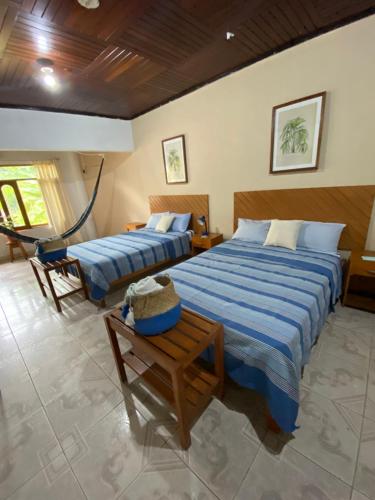 a bedroom with two beds and a chair in it at Poseidon Guest House in Iquitos