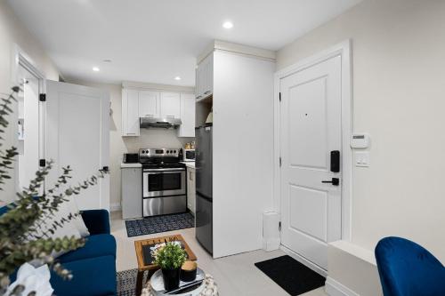 a small kitchen with white cabinets and a blue chair at Parker Guest House in Vancouver