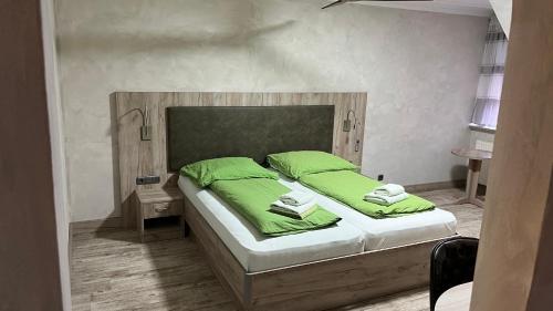 Schlafzimmer mit einem Bett mit grüner Bettwäsche und Kissen in der Unterkunft Hotel MyLord in Soltau