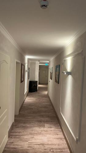 an empty hallway with a long hallway with paintings on the walls at Hotel MyLord in Soltau