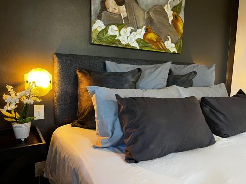 a bedroom with a bed with pillows and a painting at Tranquil Garden Nest in Nelspruit