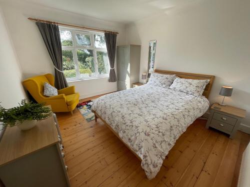 a bedroom with a bed and a chair and a window at Jamie's Georgeham in Croyde