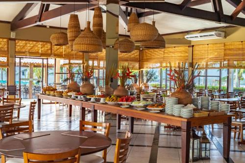 ein Restaurant mit einem langen Tisch mit Essen darauf in der Unterkunft Porto Seguro Eco Bahia Hotel in Porto Seguro