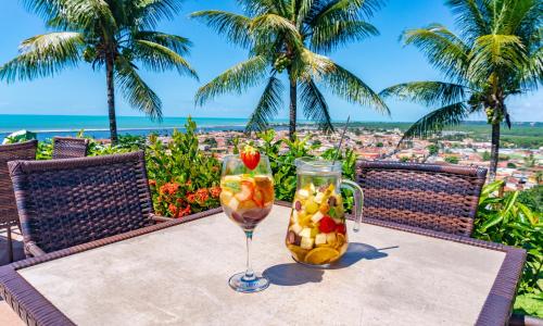 a table with a glass of wine and fruit at Porto Seguro Eco Bahia Hotel in Porto Seguro