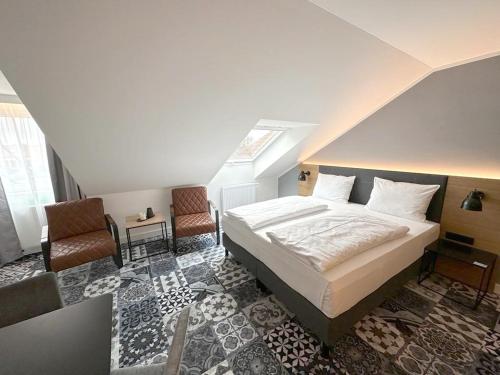 a bedroom with a bed and two chairs at Alpenglühen Smart Hotel in Olching