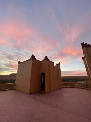 a building on a roof with a sunset in the background at Maison D'hotes Sahara in Aoufous