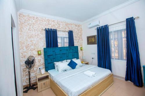 a bedroom with a blue bed with blue curtains at AJI Luxury 3BED Apartment (Ijegun, Lagos) in Lagos