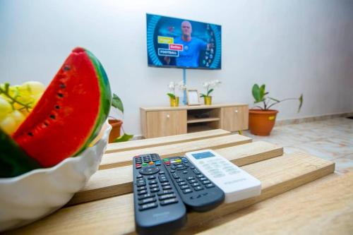 a remote control sitting on a table next to a watermelon at AJI Luxury 3BED Apartment (Ijegun, Lagos) in Lagos