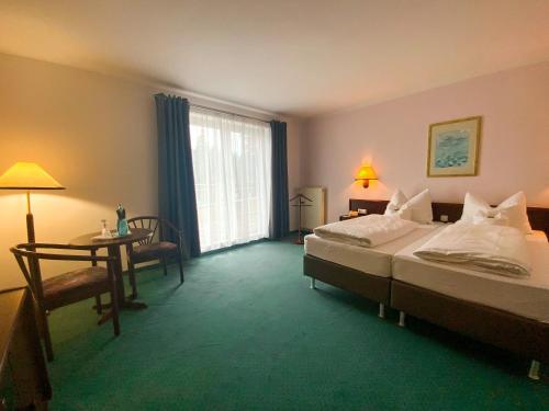 pokój hotelowy z 2 łóżkami, stołem i oknem w obiekcie Heidehotel Lubast w mieście Lubast
