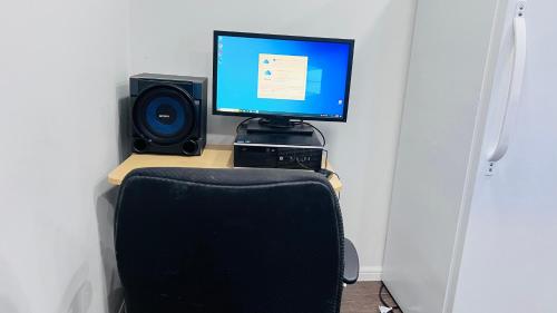 a computer monitor sitting on top of a desk with a chair at The Home Sweet Home in Winnipeg