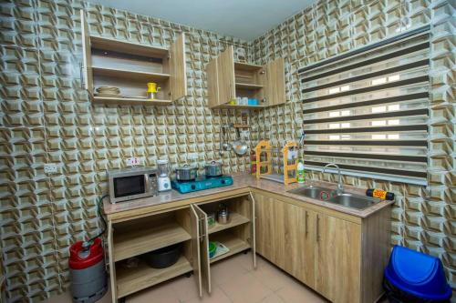 een kleine keuken met een wastafel en een magnetron bij AJI Warm 2BED Apartment (Ijegun, Lagos) in Lagos