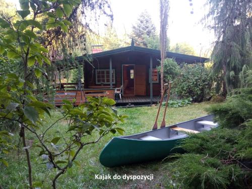 a green canoe on the grass in front of a cabin at Domek i jurta nad rzeką in Kościerzyna