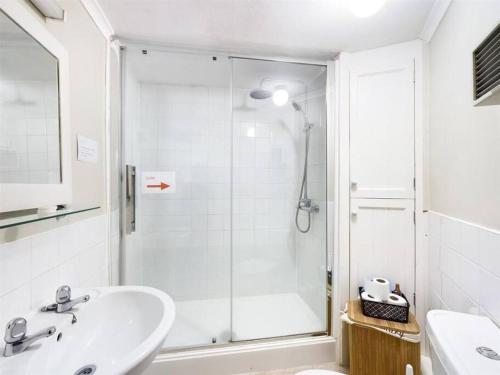 baño blanco con ducha y lavamanos en One Bed Ground Floor Apartment- Great Getaway, 