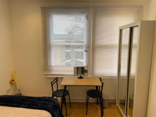 a bedroom with a table and two chairs and a window at Double Room with shared bathroom in private self-contained flat you will share with one other person in family house 2 minutes walk from Tufnell Park tube station 15 minutes walk from Camden Town in London