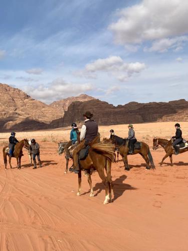 a group of people riding horses in the desert at Wadi rum Sunrise luxury camp in Wadi Rum