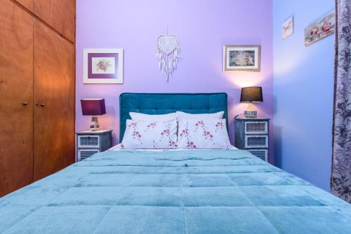 a bedroom with a blue bed with two night stands at Aegina's Flowers house in Aegina Town