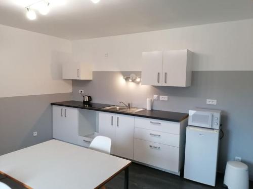 a kitchen with white cabinets and a sink and a refrigerator at Logement avec deux chambres dans maison de village 