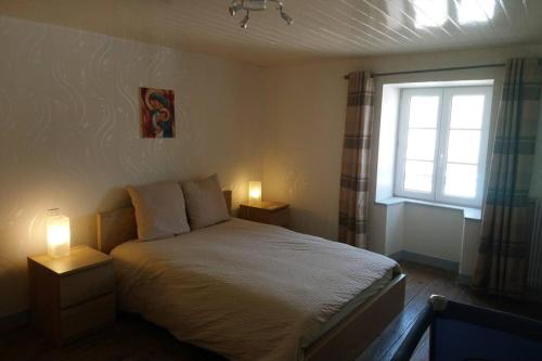 a bedroom with a bed and a window and two lamps at Logement avec deux chambres dans maison de village in Vaillant