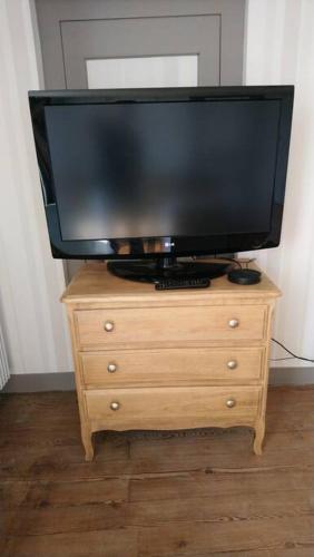 a television sitting on top of a wooden dresser at Logement avec deux chambres dans maison de village 