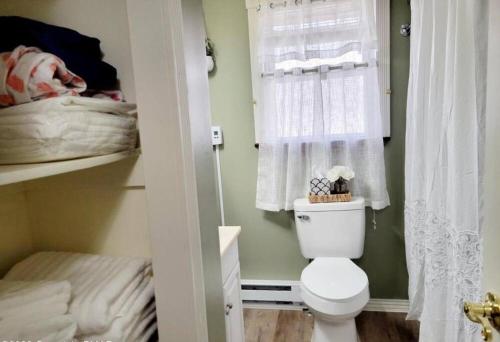 La salle de bains est pourvue de toilettes blanches et d'une fenêtre. dans l'établissement The Family Getaway, à Tobyhanna