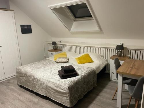 ein Schlafzimmer mit einem Bett mit gelben Kissen und einem Tisch in der Unterkunft B&B Plompetorenzicht in Burgh Haamstede