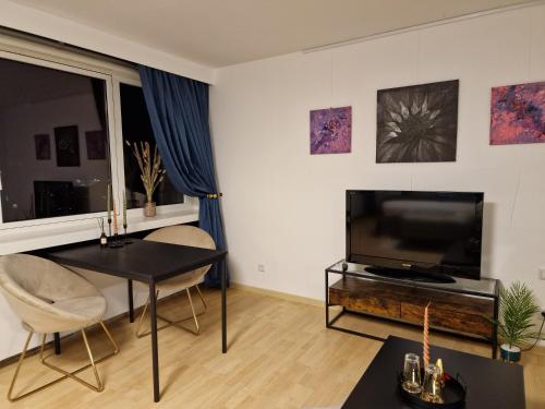 ein Wohnzimmer mit einem TV und einem Tisch in der Unterkunft 1 Zimmer Appartement im SI Centrum Stuttgart in Stuttgart