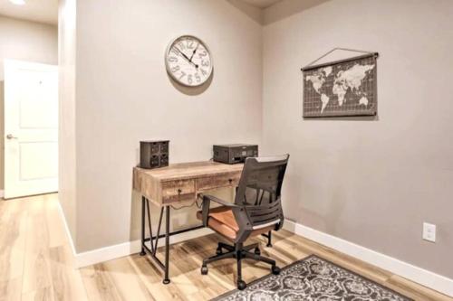 a desk with a chair and a clock on a wall at NEW! Cozy & Modern Spearfish Home Near Downtown! in Spearfish