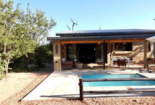 a house with a swimming pool in front of a house at Rooibos Luxury Bush Cottage in Hoedspruit