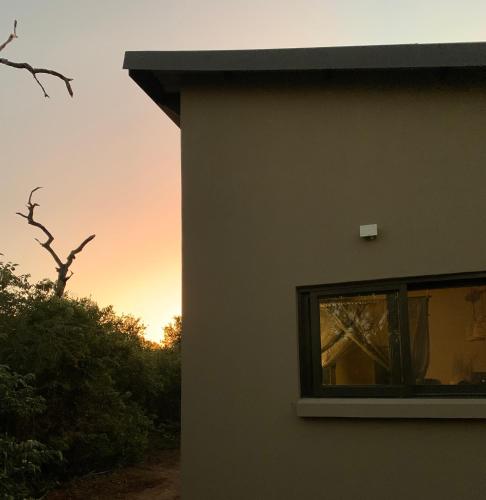 a building with a window with the sunset in the background at Rooibos Luxury Bush Cottage in Hoedspruit