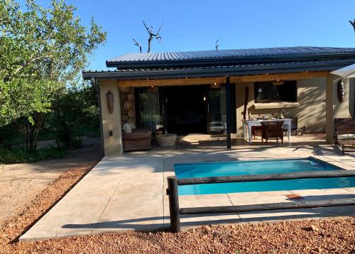 a swimming pool in front of a house at Rooibos Luxury Bush Cottage in Hoedspruit