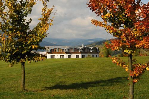 a house in a field with trees in the foreground at Grund Resort Golf and Ski in Mladé Buky