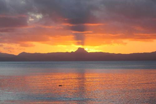 a sunset over the water with mountains in the background at Beachfront Villa - House of Bamboo, Infinity Pool in Savusavu