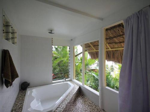 a bathroom with a tub and a large window at Beachfront Villa - House of Bamboo, Infinity Pool in Savusavu