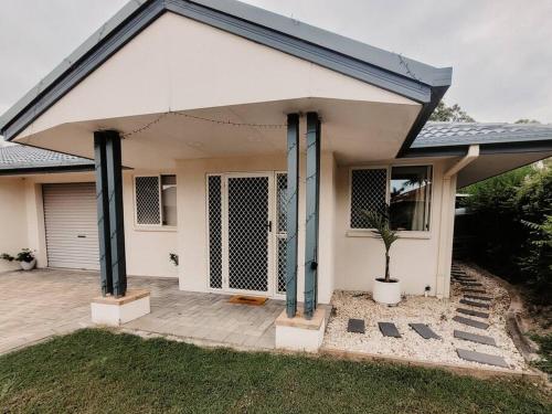 a white house with a garage and a potted plant at Pandanus Villa - #3 in Yeppoon