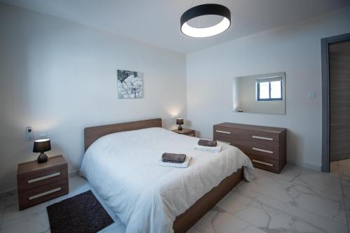 a bedroom with a bed and two dressers and a mirror at Seaside Luxury Apartment in St Paul's Bay